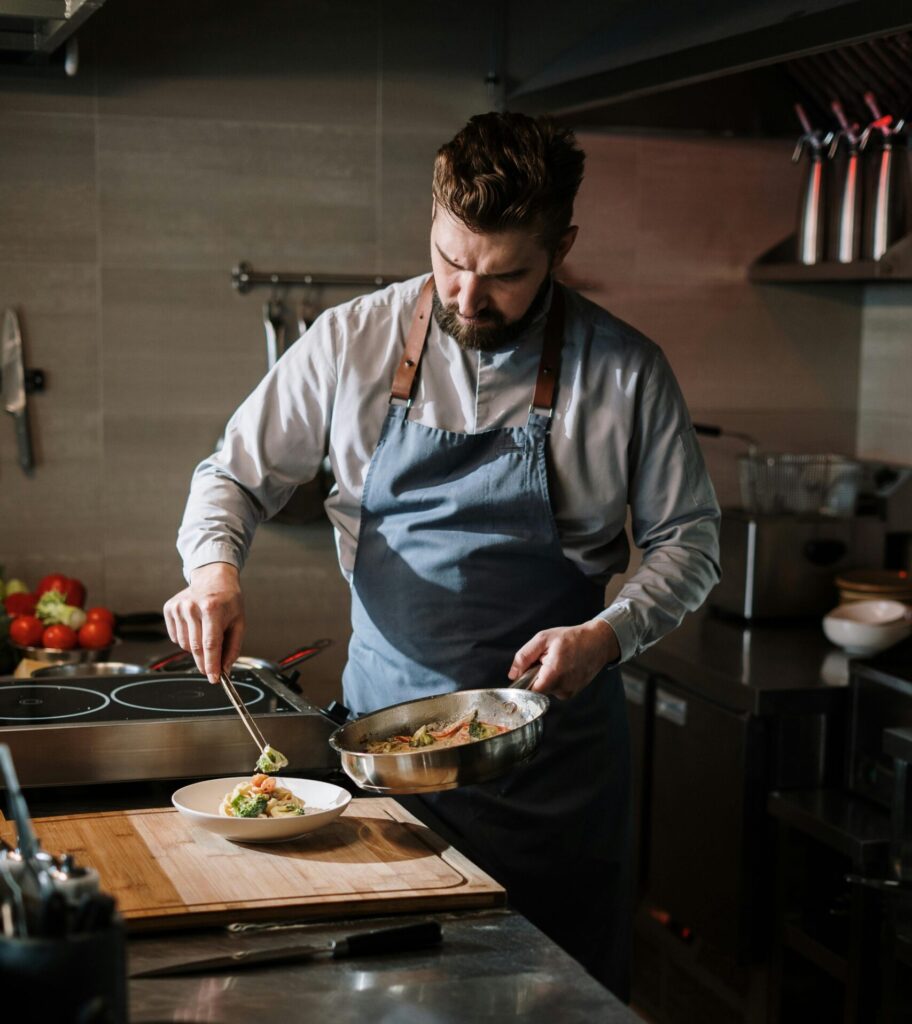 Professional chef plating a gourmet dish in a modern kitchen setting.