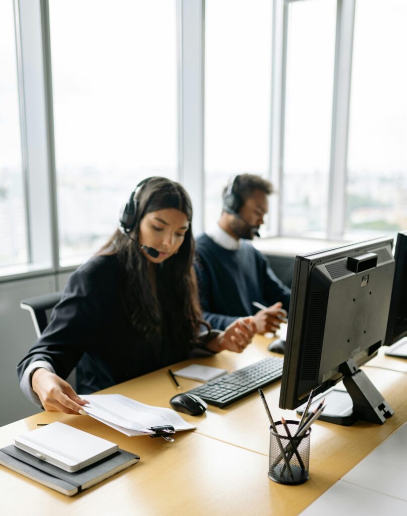 Call center agents handling customer inquiries at modern office desks, focused and professional.